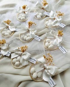 wedding favors with white flowers and gold rings on top of a bed sheet, surrounded by tags