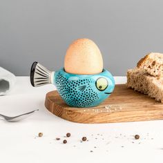 an egg cup sitting on top of a cutting board next to a piece of bread