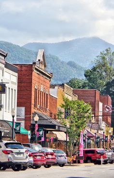 cars are parked on the street in front of buildings with mountains in the back ground