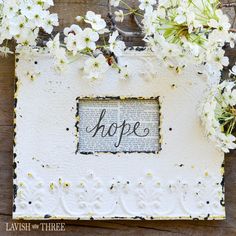 an old book with the word hope written on it surrounded by white flowers and greenery