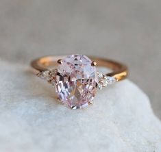 a pink diamond ring sitting on top of a rock