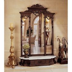 an ornately decorated mirror on the wall next to a candle holder and vase with flowers