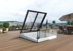 an umbrella and some chairs on a deck with a roof top bar in the background