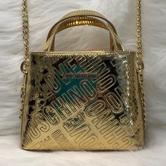 Nwot This Small Love Moschino Satchel Is Super Cute! For A Small Bag It Is Mighty In Fashion! Fits 6.5”Cell Phone At An Angle, Keys, Small Wallet, And A Few Accessories Comes In Gold Patent & Black Interior With Chain Link Strap. Convert From A Satchel To A Crossbody! New, Excellent Condition! Features: Love Moschino Color Gold Signature Logo Strap Length 52 Inches Drop 25” Interior Black Signature Lining Gold Logo Lettering Gold-Tone Hardware Concealed Magnetic Closure Double Circular Top Handle Detachable Shoulder Strap Internal Slip Pocket Partitioned Compartment Measures 9"H X 7.5”W X 2.5”D Measures Without Handles, 5.7/8” Clean With Damp Cloth Retails For $350 Asking $2 Gold Tote Bag With Logo Hardware, Gold Shoulder Bag With Logo Hardware For Shopping, Gold Shoulder Bag With Logo For Evening, Gold Bags With Logo Hardware, Evening Gold Bags With Logo Hardware, Gold Evening Shoulder Bag With Logo, Gold Evening Bags With Logo Hardware, Gold Crossbody Bag With Logo, Gold Logo Crossbody Bag