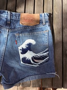 a pair of jeans with the great wave painted on them