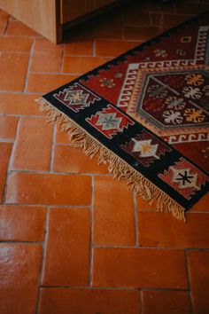 a red and black rug sitting on top of a floor next to a wooden cabinet