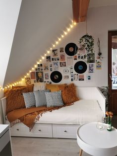 a white couch sitting under a slanted ceiling with lots of pictures on the wall