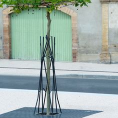 a tree that is standing in the middle of some sort of metal structure with leaves on it