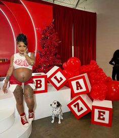 a pregnant woman standing in front of red blocks with the word booze spelled on them