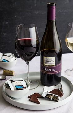 a bottle of wine and some chocolates on a plate with two glasses of wine