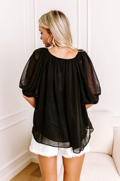 - Bask in a chic midtown moment with this airy top! - Unlined, double layered sheer chiffon material - A v-cut neckline with a tie detail - Short, loose sleeves with elastic cuffs - A flowy silhouette that ends in a curved hemline Flowy Solid Chiffon Blouse, Chic Black Peasant Top For Spring, Flowy Chiffon Tops, Flowy Black Top For Layering, Chic Chiffon Tops For Night Out, Flowy Blouse For Layering, Black V-neck Tops With Sheer Sleeves, Black V-neck Blouse With Sheer Sleeves, Flowy Chiffon V-neck Blouse