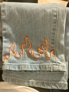 a pair of jeans with embroidered flames on them