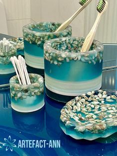 three toothbrushes are sitting in cups with seashells on them