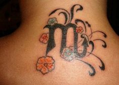 the back of a woman's neck with flowers on it and an m in the middle