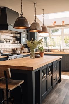 a kitchen with two pendant lights hanging from the ceiling and an island in front of it