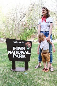 a woman standing next to a little boy in front of a sign that says finn national park