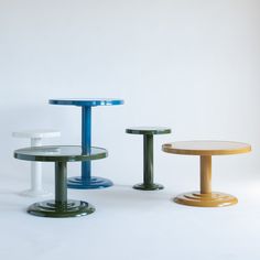 three different colored tables sitting next to each other on a white surface in front of a wall