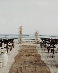 an outdoor ceremony setup on the beach with white flowers and greenery in vases