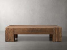 a wooden bench sitting on top of a cement floor next to a white wall in an empty room