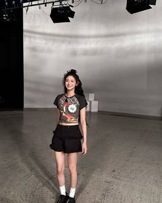 a woman standing in an empty room with lights on the ceiling and lighting behind her