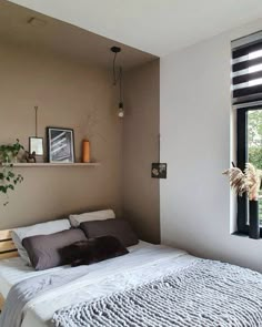 a bed sitting next to a window in a bedroom under a skylight with plants on the ledge