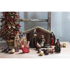 a nativity scene with figurines in front of a christmas tree and other decorations