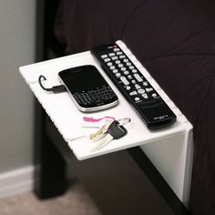 two cell phones are sitting on top of a small table with keys and remotes