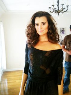 a woman standing in a living room wearing a black dress