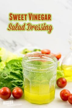 a jar filled with salad dressing next to tomatoes and lettuce on a table