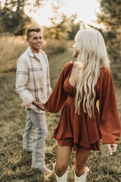 a man and woman standing in the grass holding hands