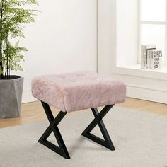 a pink foot stool sitting on top of a rug next to a potted plant