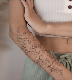 a woman's arm with flowers on it and her hand holding the other arm