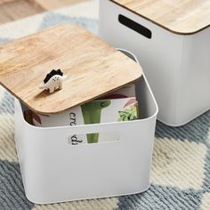 two white storage containers with wooden lid and small animal figurines sitting on top