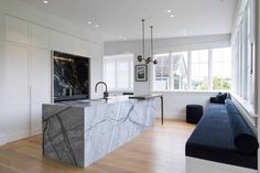 a large kitchen with marble counter tops and white cabinetry, along with blue couches