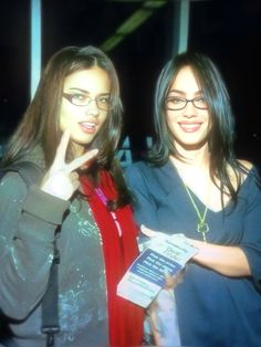 two young women standing next to each other holding something in their hands and posing for the camera