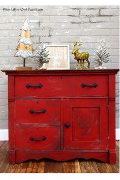 an old red dresser with christmas decorations on top and a deer figurine next to it