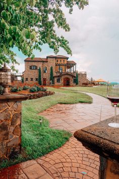 a glass of wine sitting on top of a brick patio next to a stone wall