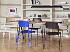 three chairs are sitting in front of a table with bookshelf behind them and shelves