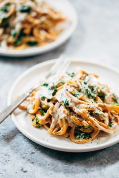 a white plate topped with pasta covered in sauce and vegetables next to a silver fork