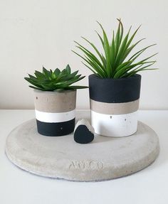 two potted plants sitting on top of a white table next to a black heart