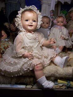 a group of dolls sitting next to each other on top of a shelf in a room