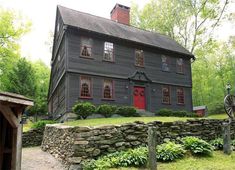 an old black house with red doors and windows