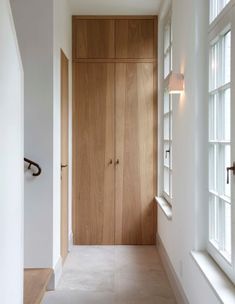 an empty hallway with wooden doors and white walls