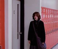 a woman is standing in front of lockers holding a purse and looking at the camera