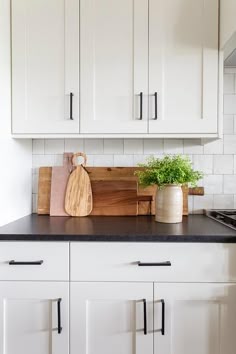 a kitchen with white cabinets and black counter tops is pictured in this image the cutting board has a wooden paddle on it