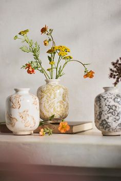 three vases with flowers in them are sitting on a table next to a book