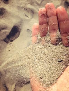 someone is holding their hand out in the sand