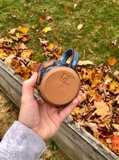 someone is holding up their shoes in front of the leaves on the ground and grass