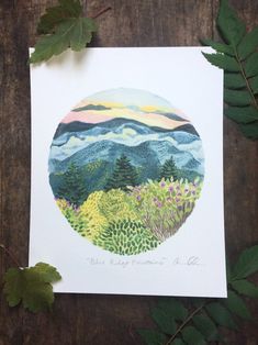 a card with an image of mountains and trees in the background, surrounded by leaves