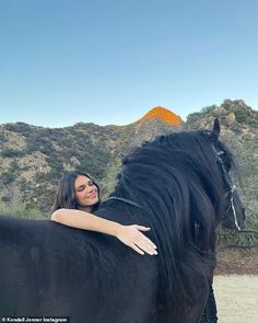 a woman sitting on top of a black horse